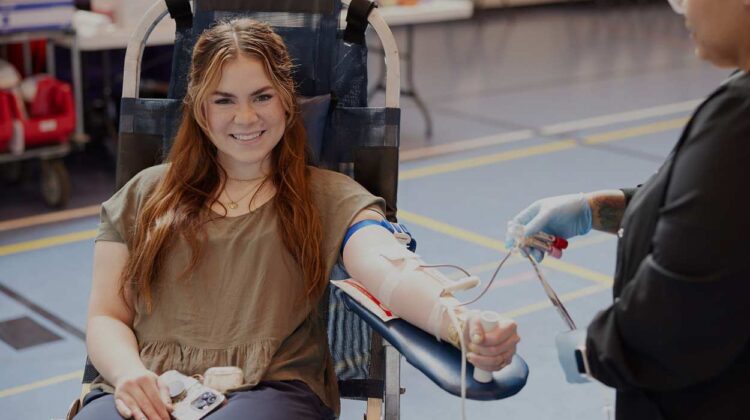Blood donor seated in chair, giving blood
