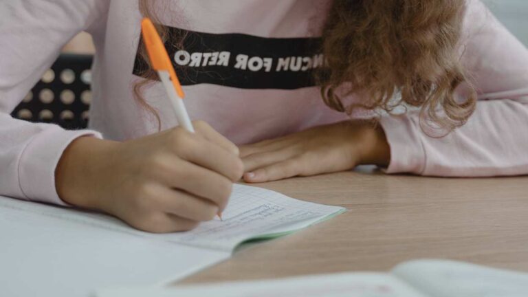 Close up of student writing in notebook at desk
