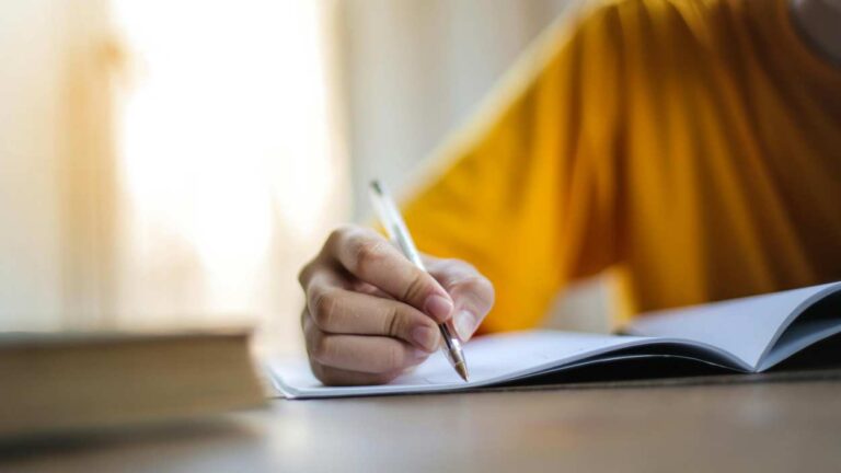 Close up of person writing in notepad for story about considering curriculum to help students write better