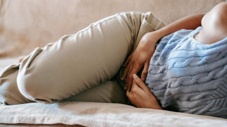 Person lying on couch holding stomach
