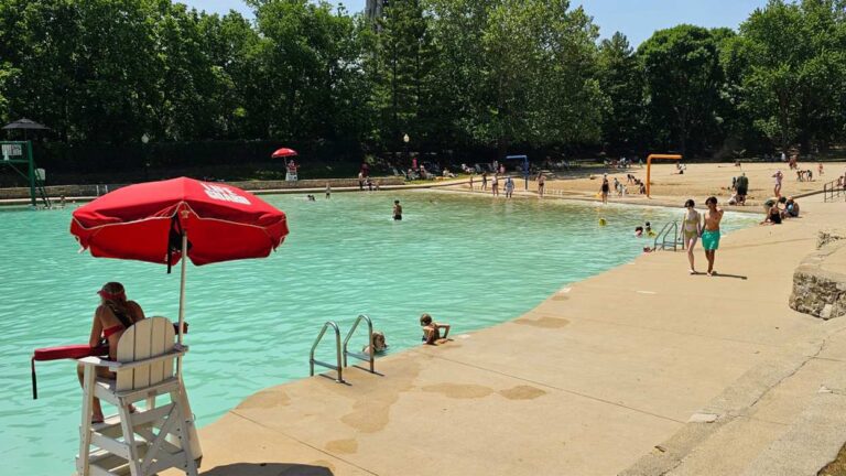 Wide shot of Naperville's Centennial Beach with lifeguard station and kids walking next to water