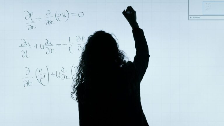 Outline - dark profile from behind of a teacher/educator writing equations on a whiteboard