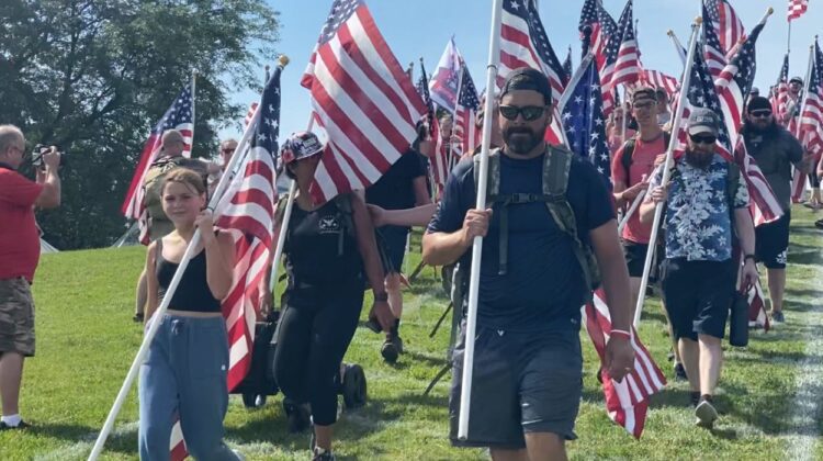 People carry flags down Rotary Hill. Naperville Salute canceled for summer 2025