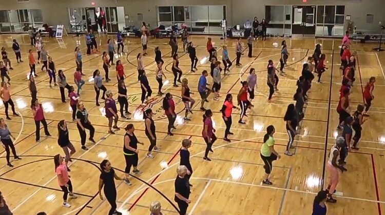 Wide shot of Naperville Park District gym with group of women in lines working out in the indoor space