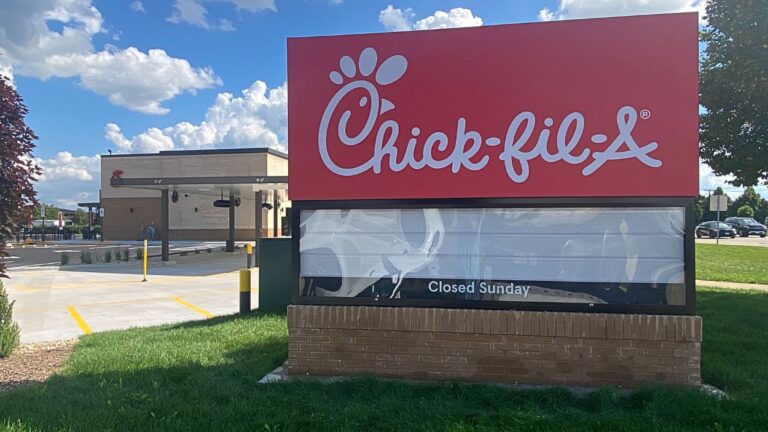 Close up of Chick fil A sign with new Chick fil A restaurant in background on left