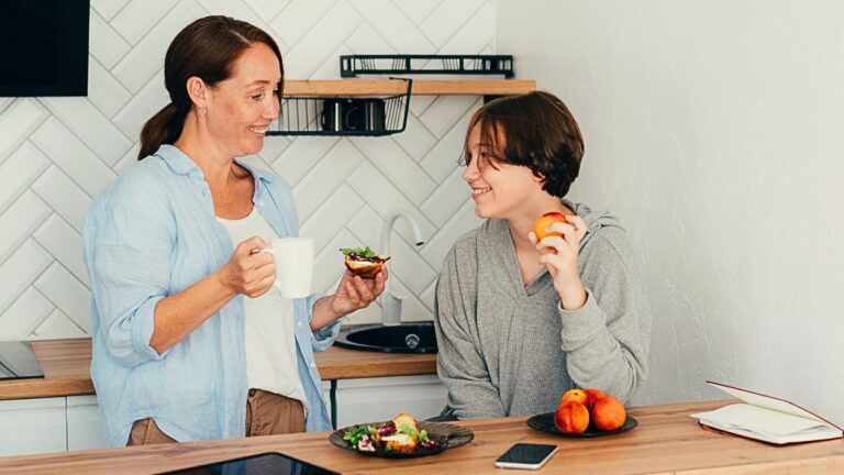 Mom talks to her teenage son over breakfast at a kitchen counter