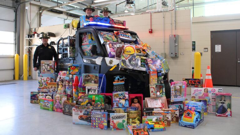 Naperville Park District Police officers stand by vehicle surrounded by toys collected for Toys for Tots program
